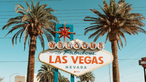 Das Schild "Welcome to Fabulous Las Vegas, Nevada" steht zwischen zwei Palmen unter einem klaren Himmel.
