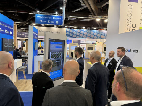 Eine Gruppe von Menschen beobachtet einen Bildschirm auf einem Technologie-Expo-Stand.