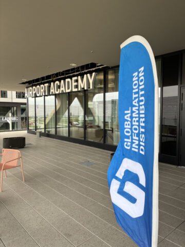 Eine Flagge mit der Aufschrift Global Information Distribution steht vor einem Gebäude mit der Aufschrift Airport Academy.