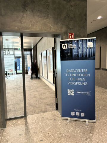 Ein Banner für Rechenzentrumstechnologien von Dell steht in der Nähe einer Tür in einem modernen Korridor.