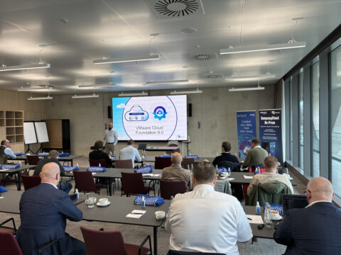 Teilnehmer an einer Präsentation über VMware Cloud Foundation 9.0 in einem modernen Konferenzraum.