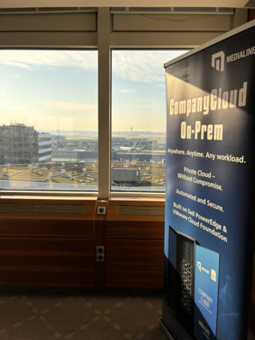 Ein Werbebanner für CompanyCloud On-Prem steht an einem Fenster mit Blick auf die Gebäude der Stadt.